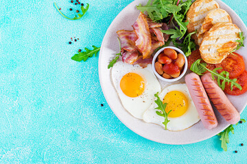 English breakfast - fried egg, beans, tomatoes, sausage, bacon and toast. Top view, flat lay, overhead