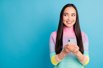 Portrait of attractive cheerful girl using gadget looking aside copy space isolated over bright blue color background