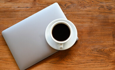 Fototapeta na wymiar White coffee mug placed on the laptop on a wooden table.