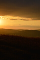 Fototapeta na wymiar Sunset in the wild, mountain twilight orange light, landscape, clouds and the sky.