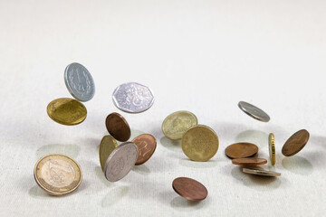 Different countries coins falling down on the white canvass surface. Coins levitating in the air