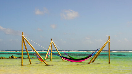 Colorful Hammocks on the bamboo construction in the shallow and clear sea water. Relaxation in the sun