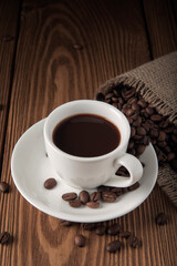 Cup of coffee with beans on wooden textured table