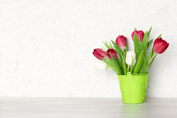 Tulip flower bouquet on the table against the wall. Copy space. Spring background
