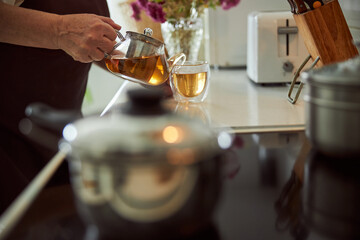 Fototapeta na wymiar Elderly woman pouring herbal tea into cup