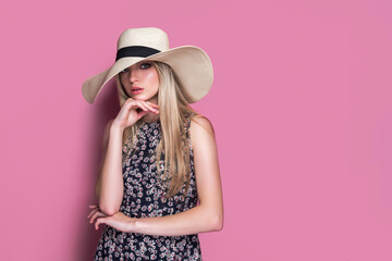 Beauty photo of attractive sensual woman wearing straw brimmed hat, posing on pink studio background. Girl with glamour makeup.