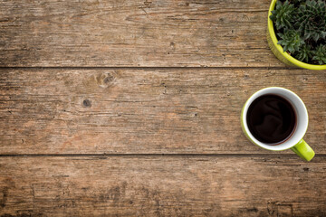 Rustic wooden background with cup of coffee and houseplant, top view