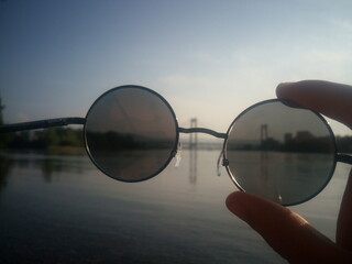 Fototapeta na wymiar Sunglasses in hand on the background of the river