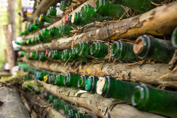 fence in the forest made of logs and glass wine bottles, champagne