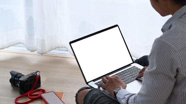 Cropped shot of photographer is working with latop on the floor. Blank screen for graphics display montage.
