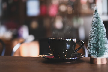 A cup of coffee or tea  and Christmas tree on wooden table.