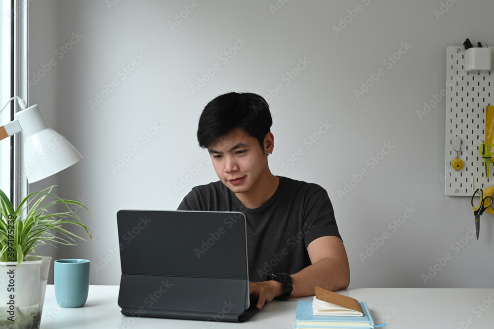 Poster front view of a graphic designer is working on computer tablet at his creative workspace.