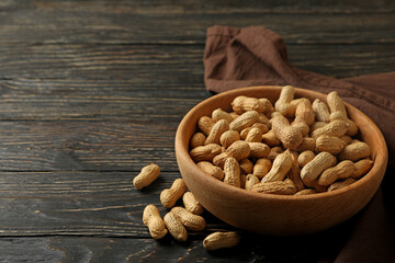 Napkin and bowl with peanut on wooden background
