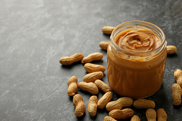 Peanut and jar with peanut butter on black smoky background
