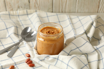 Napkin with peanut, jar of peanut butter and spoons