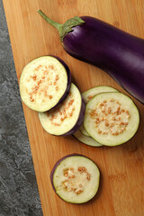 Board with eggplants on black smokey background