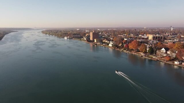 Boat Cruising At Detroit River Passing By The City Of Wyandotte In Autumn In Michigan, USA. - aerial