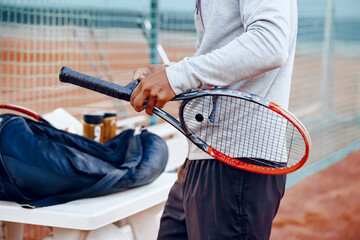 Unrecognizable tennis player repairs coverage of handle of tennis racket
