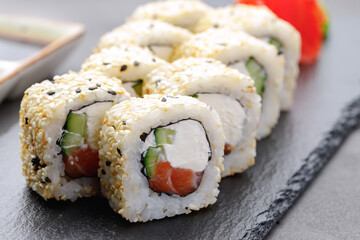 Sushi roll with salmon, philadelphia cheese and sesame on plate close up