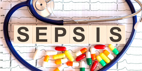 Wooden blocks with the inscription SEPSIS with a stethoscope,pills