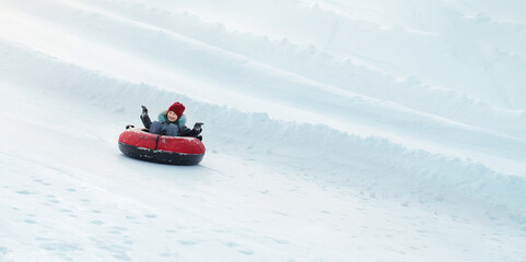 Child loving sledding down a steep hill during a snowly winter.