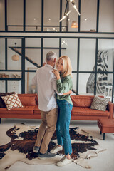 Mature couple dancing in the room and looking happy