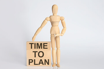 Wooden man shows with a hand text TIME TO PLAN on wooden block