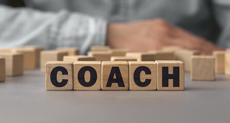 The word COACH made from wooden cubes. Shallow depth of field on the cubes