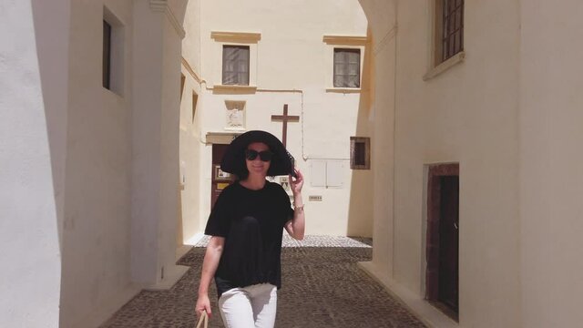 Woman walk on Street at St. John the Baptist Cathedral in Santorini, slow motion