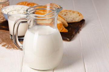 Glass jar of milk, bowl of cottage cheese and bread on wooden table