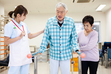 歩行訓練を頑張る高齢男性とサポートをする奥さん、女性看護師
