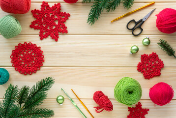 Christmas flat lay of items for needlework. Knitted snowflakes, threads and hooks on wooden...