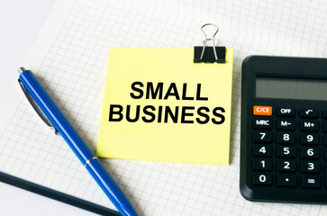 Calculator with a blue pen and a yellow sticker with text Small Business lie down on notepad