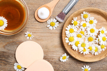 Naklejka na ściany i meble Flat lay composition with chamomile flowers and cosmetic products on wooden table