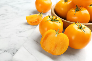 Ripe yellow tomatoes on white marble table, closeup. Space for text