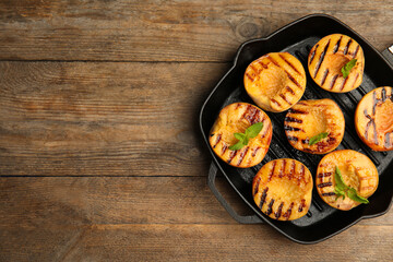 Delicious grilled peaches with mint on wooden table, top view. Space for text
