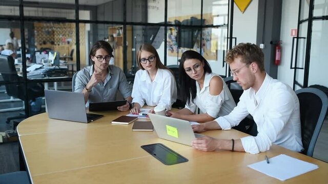 Modern young business people in formal clothes working in the office by using laptops and documents.