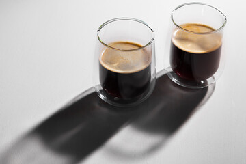 Americano coffee in glass cups on white background with long shadows