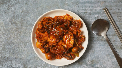 Fried squid with Korean spicy sauce on gray concrete table.