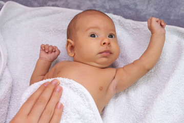 The mother wipes the baby with a towel after bathing