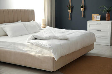 Obraz premium Comfortable bed with soft blanket in stylish room interior