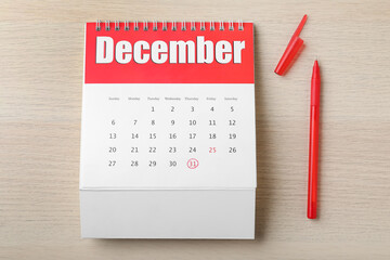 Calendar with marked date and pen on wooden table, flat lay. New Year countdown