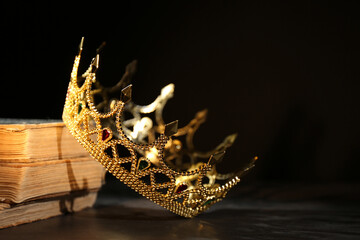 Beautiful golden crown and old books on black table. Fantasy item © New Africa