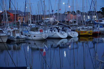 boats in marina on a full moon evening with mirror reflection in the water in Brittany, France