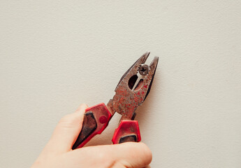 Close up view of person hand removing old plastic dowel, nylon wall plug from drywall with pliers...