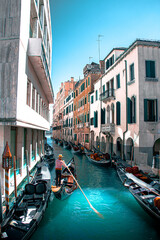 Fototapeta na wymiar Summer in Venice, Italy. View of old buildings, narrow streets and bridges. Monuments of one of the most beautiful cities in Italy. Gondolier 