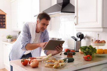 Man cooking consulting recipes on a tablet