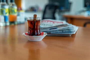 A glass of Turkish tea and newspaper on the wooden table.