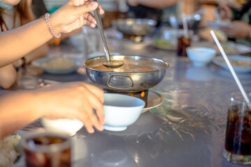Blurred abstract background of hands eating on a table like seafood (Baked shrimp vermicelli, deep fried sea bass with fish sauce, yum squid) eaten alongside soft drinks, while on vacation with family