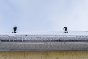 chimneys on the roof. the roof of a private house is covered with snow and frost.